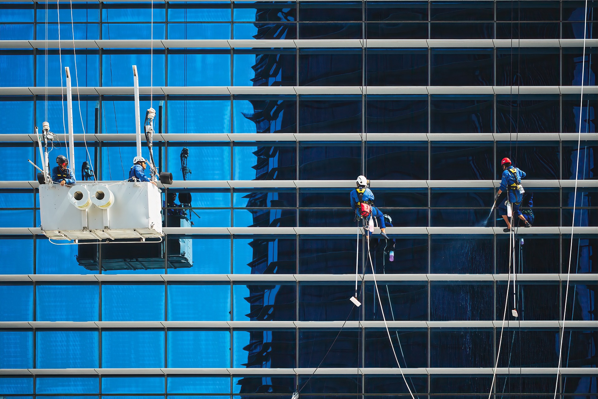 Operarios limpiando la fachada acristalada de un edificio de oficinas