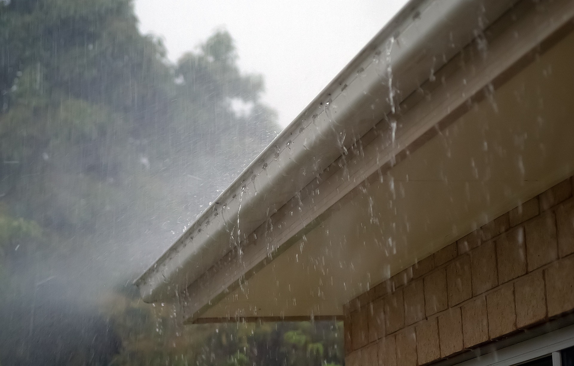 Lluvia intensa cayendo sobre el alero y el canalón de un edificio
