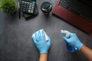 Desinfección de un puesto de trabajo con guantes y pulverizador en una oficina